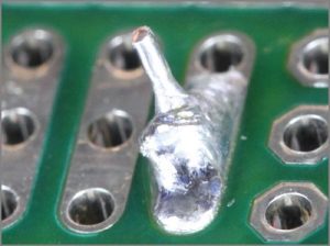 A close-up of a defective cold solder joint on a circuit board.